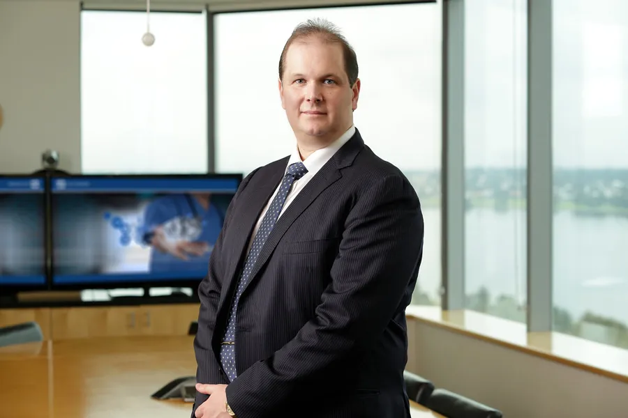Nathan Buzza in a boardroom with Alcidion clinical-imaging display behind him.